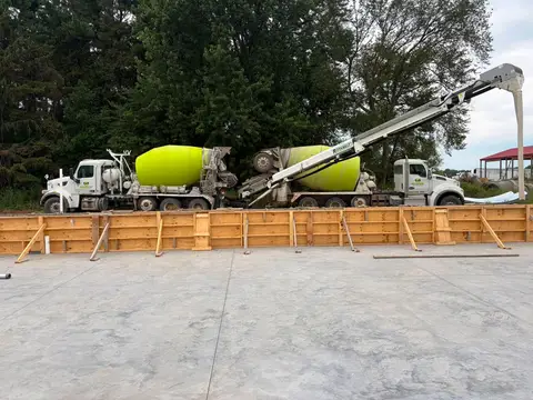 Concrete mixers pouring into a foundation form with wooden frames