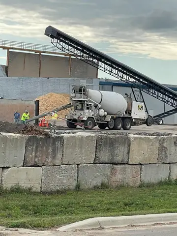 Concrete mixer truck pouring at a site with a conveyor belt