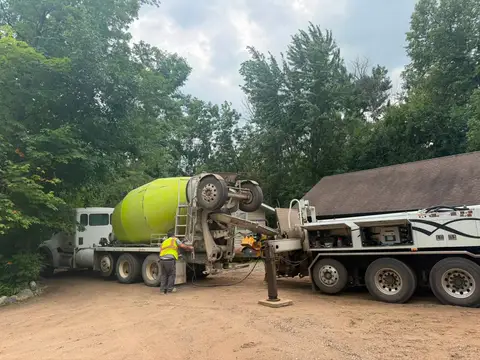 Worker operating a concrete mixer truck in a wooded area