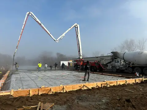 Workers pouring concrete into a foundation with a pump truck